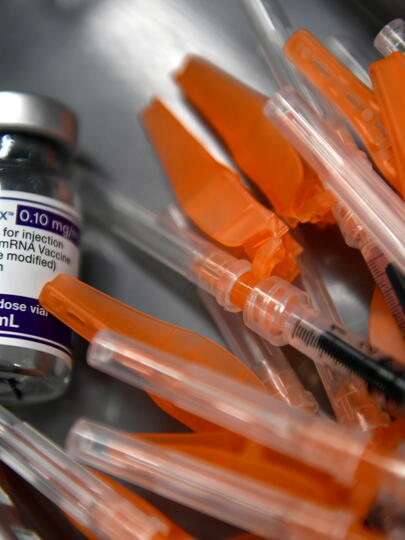 A vaccine bottle beside several syringes