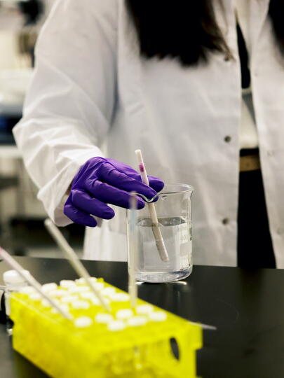 Researcher holding stir stick submerged in some liquid in a beaker