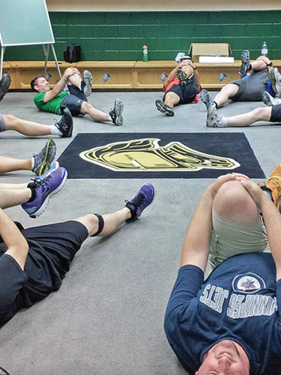 Men doing stretches lying on floor of a changeroom