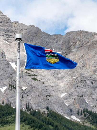 Alberta and Canadian flags in front of mountains