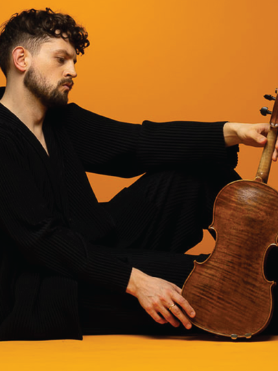 Man in black clothing sitting on ground with viola