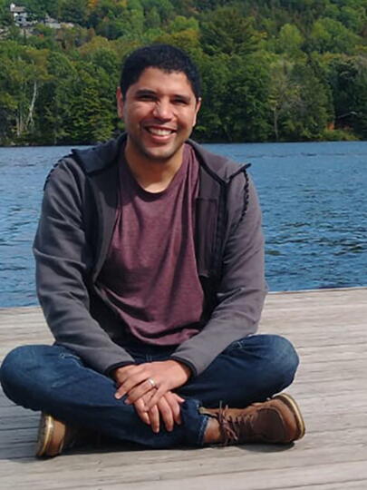 Hugo Mota Santos seated on a deck with water and trees in the background
