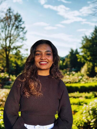 Smiling woman standing against a garden backdrop