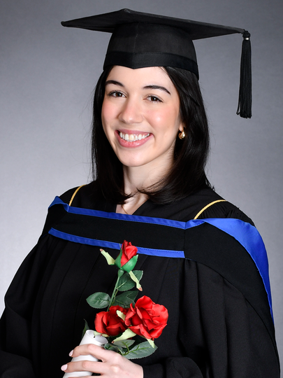 Woman in graduation cap and gown carrying roses