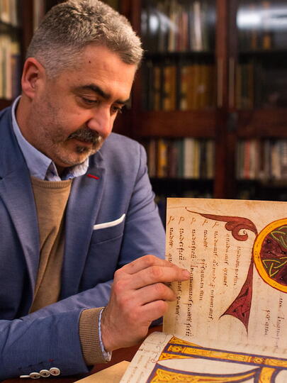 Man looks at large book in library