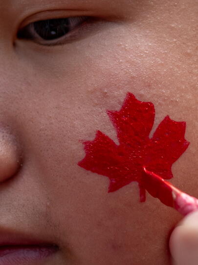 Canadian maple leaf being painted on boy's cheek