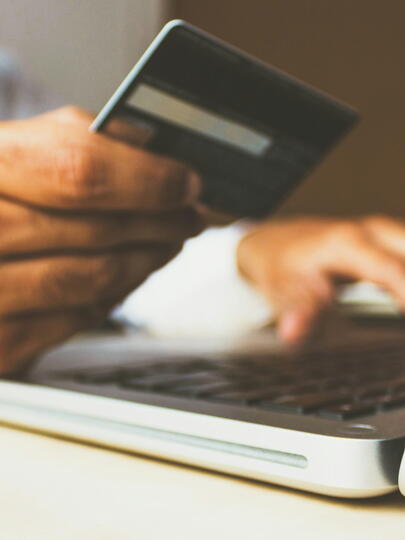 Man holds credit card while typing on laptop