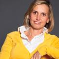 Elena Giorgetti in a yellow sweater against a grey background.