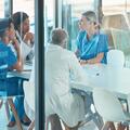 A group of doctors sit at a table discussing a patient's care