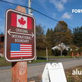 A road sign with the Canadian and American flags, signalling the crossing of an international boundary.